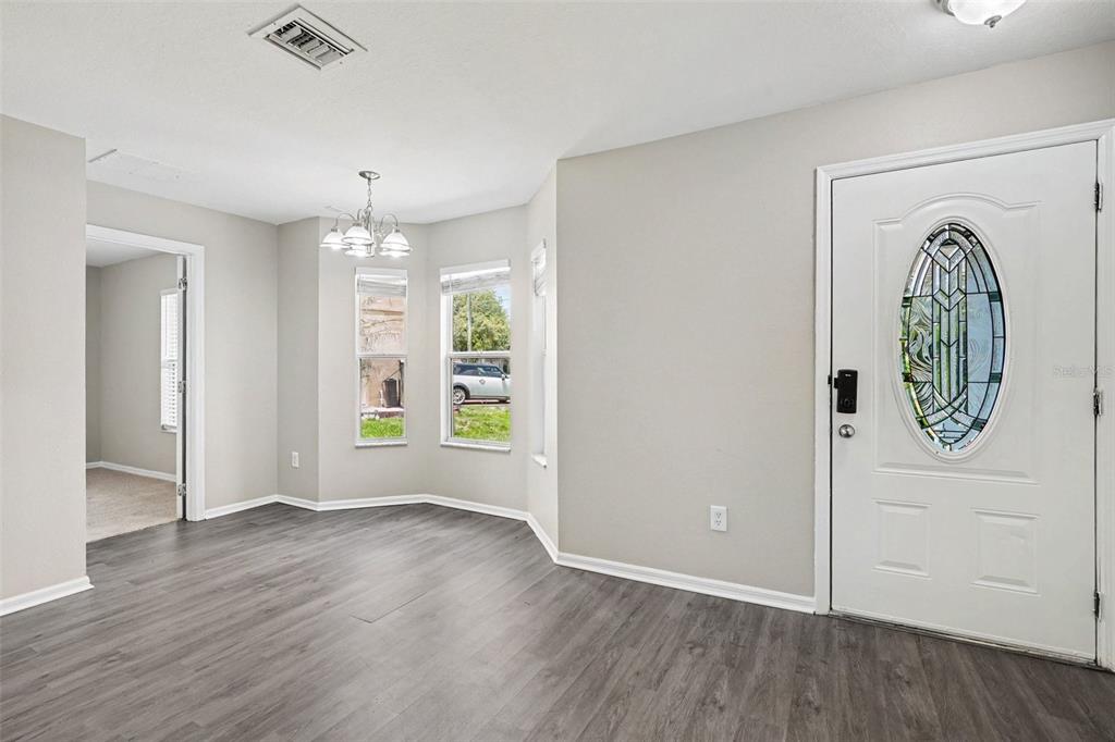 An entryway with gray wood-look flooring, a white front door, and a dining nook area — 449 DANUBE DRIVE, KISSIMMEE, FL