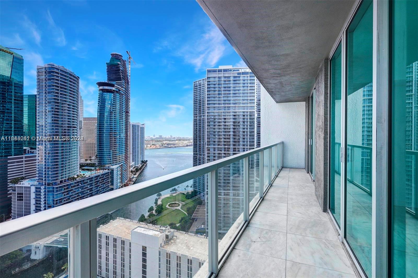 A high-rise apartment balcony with a glass railing overlooks a city skyline and water — 55 SE 6th St # 3401, Miami FL 33131, MIAMI, FL