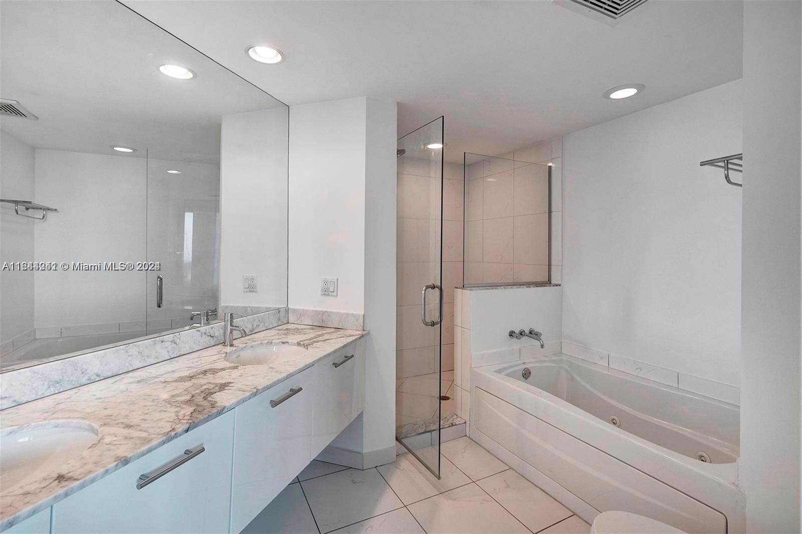 A modern bathroom features a double vanity with marble countertops, a glass shower, and a tub — 55 SE 6th St # 3401, Miami FL 33131, MIAMI, FL