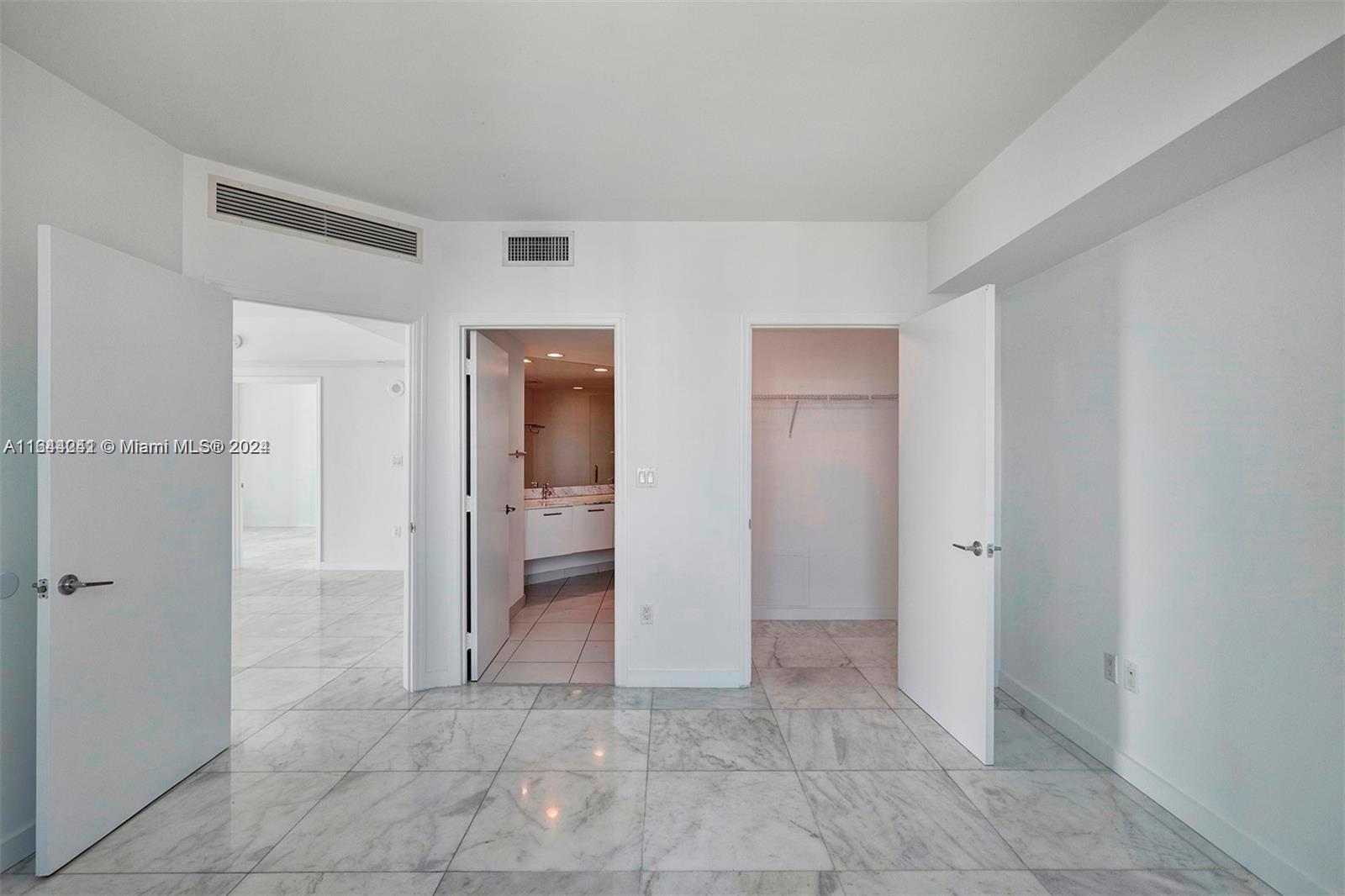 A room with white walls, marble flooring, two open doorways, and a closet door — 55 SE 6th St # 3401, Miami FL 33131, MIAMI, FL