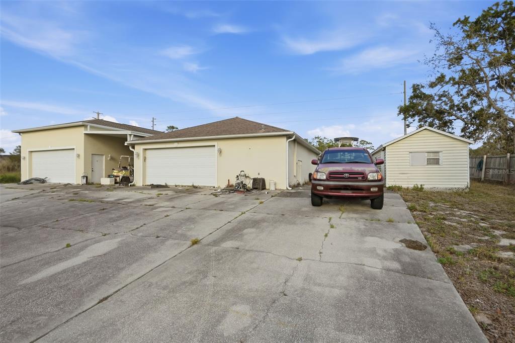 A concrete driveway leads to a house with two garages and a detached storage shed — 8038 MADRID ROAD, WEEKI WACHEE, FL