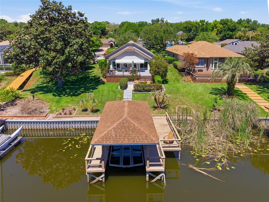 An aerial view shows a waterfront house with a boat dock and a grassy backyard — 6120 LANDINGS BOULEVARD, LADY LAKE, FL