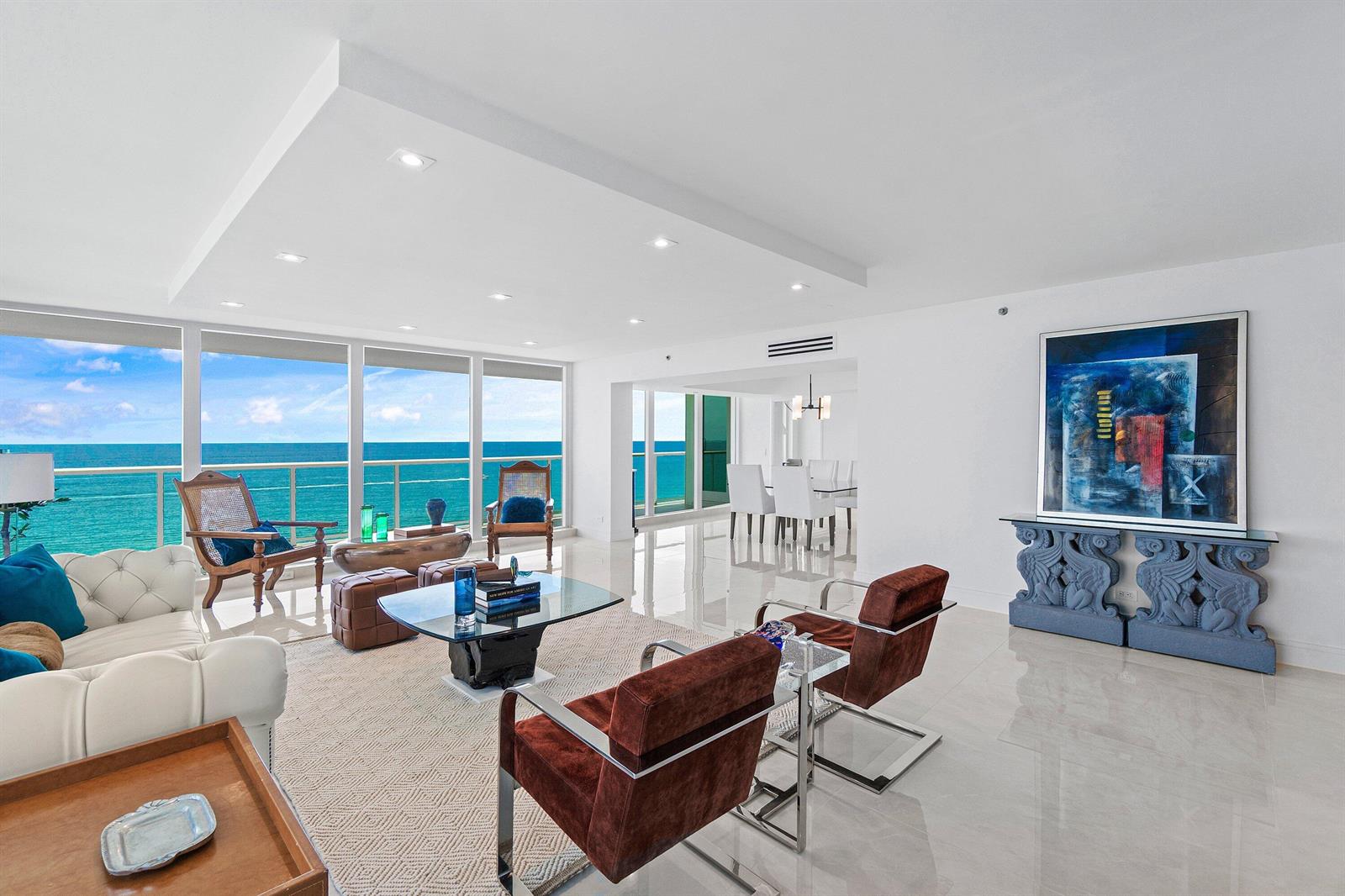 A bright living room features white tile floors, modern furniture, and floor-to-ceiling ocean views — 3505 S Ocean Boulevard # 12n, Highland Beach FL 33487, HIGHLAND BEACH, FL