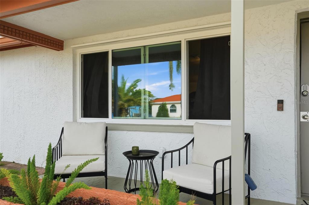 A small patio features two white chairs and a side table beneath a large window — 7628 DALE DRIVE, PORT RICHEY, FL
