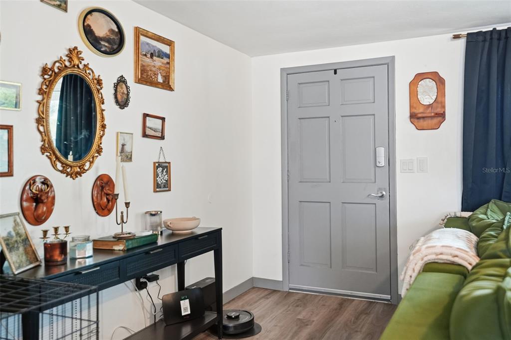 A living room features a grey door, a gallery wall, and a black console table — 7628 DALE DRIVE, PORT RICHEY, FL