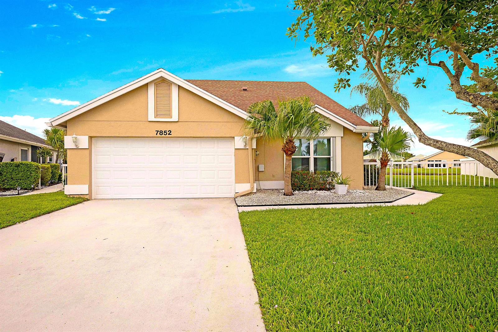 A single-story house with a beige stucco exterior, a two-car garage, and a front lawn — 7852 Lake Champlain Court, Delray Beach FL 33446, DELRAY BEACH, FL