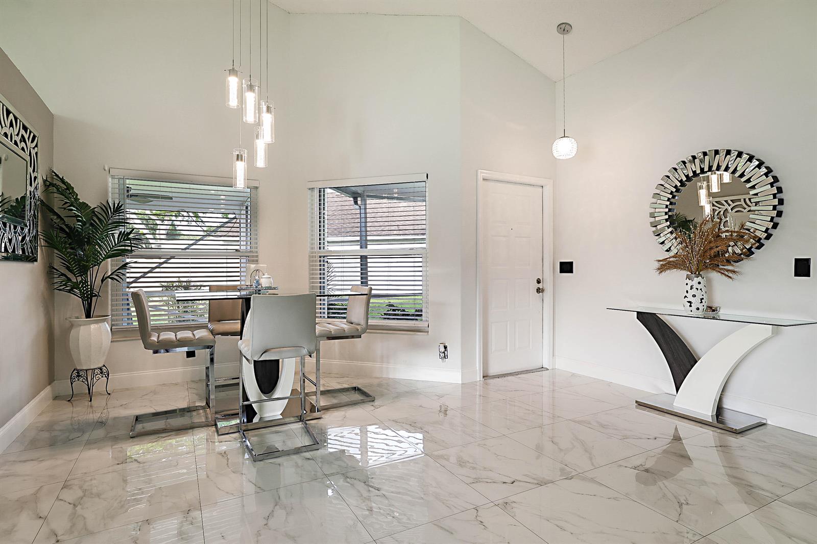 A dining area with a glass table, modern chairs, and white marble-look tile flooring — 7852 Lake Champlain Court, Delray Beach FL 33446, DELRAY BEACH, FL