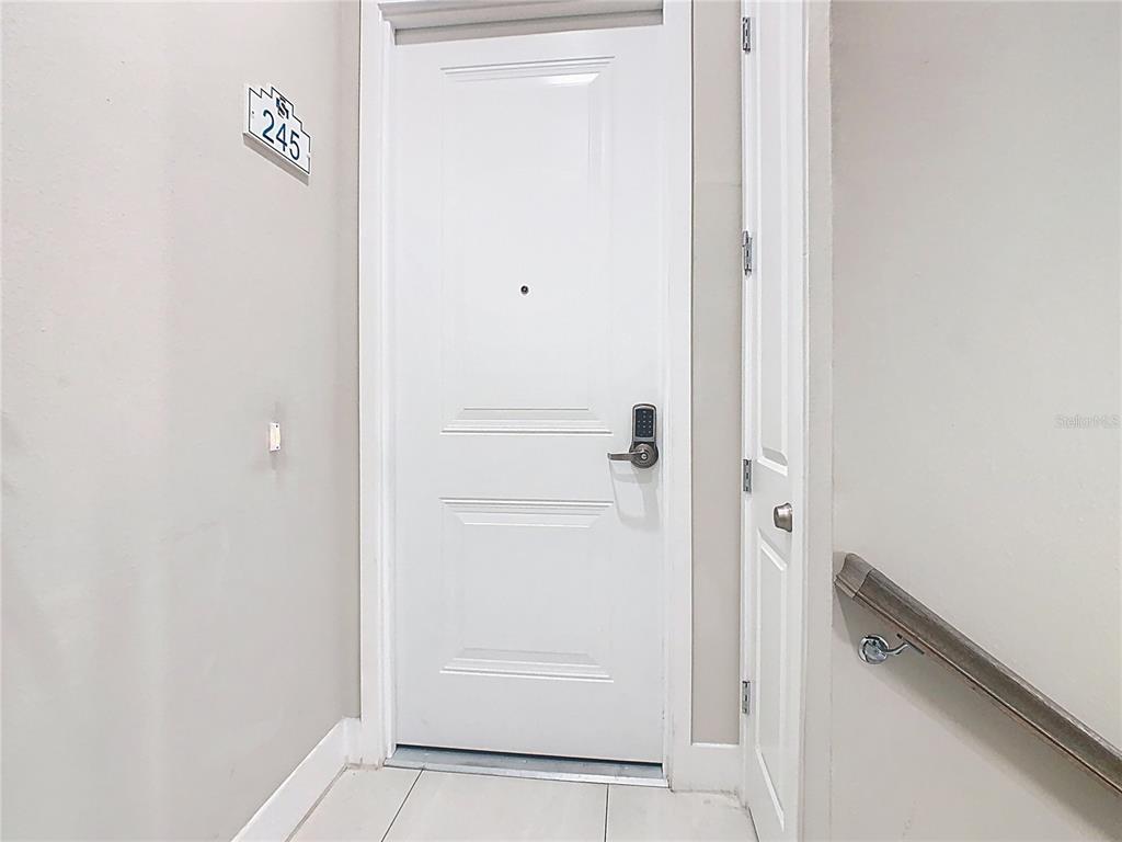 A white door with a digital lock and a unit number sign 245 above it — 7740 SANDY RIDGE DRIVE UNIT 245, REUNION, FL