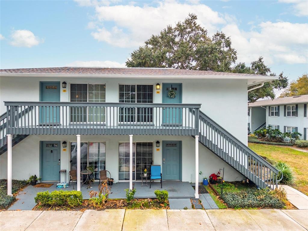 A two-story apartment building features light blue exterior walls, a wooden balcony, and exterior staircases — 4870 CONWAY ROAD UNIT 106, ORLANDO, FL
