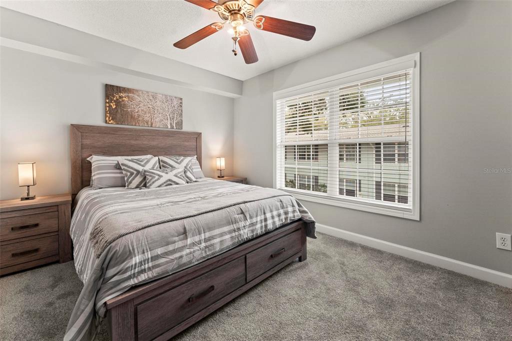 A bedroom features a wooden bed frame, gray carpet, a ceiling fan, and a window — 4870 CONWAY ROAD UNIT 106, ORLANDO, FL