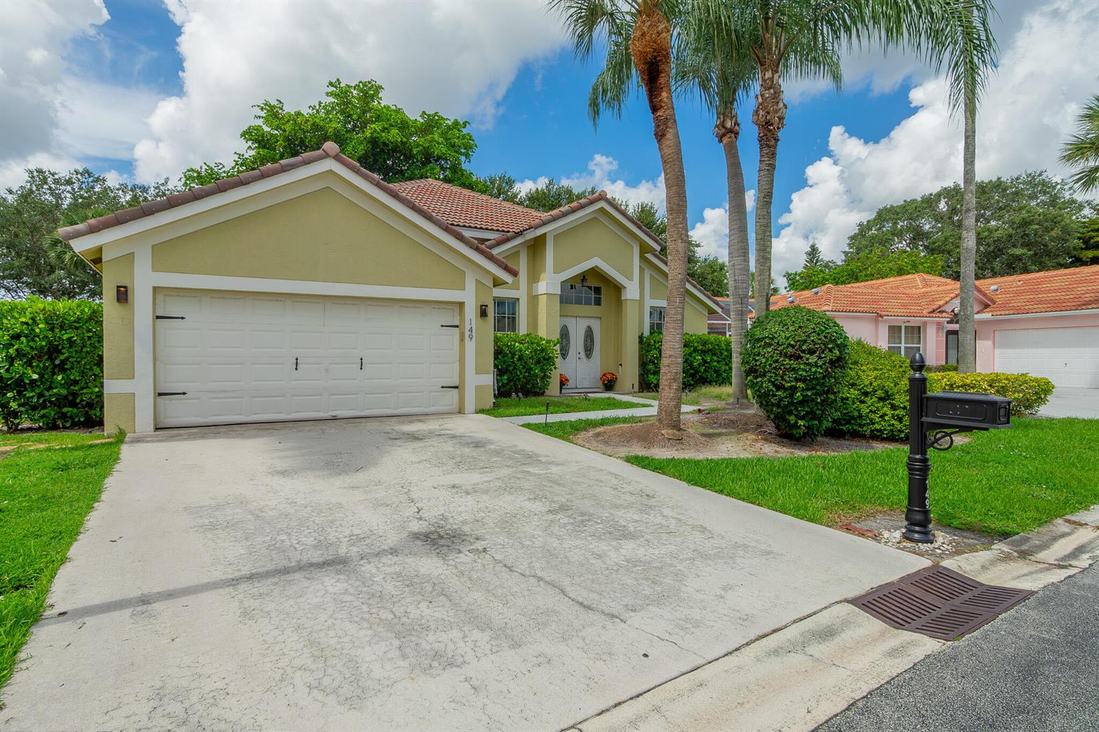 A single-story house with a white garage door, tan stucco walls, and a tiled roof — 149 Cove Road, FL 33413, FL