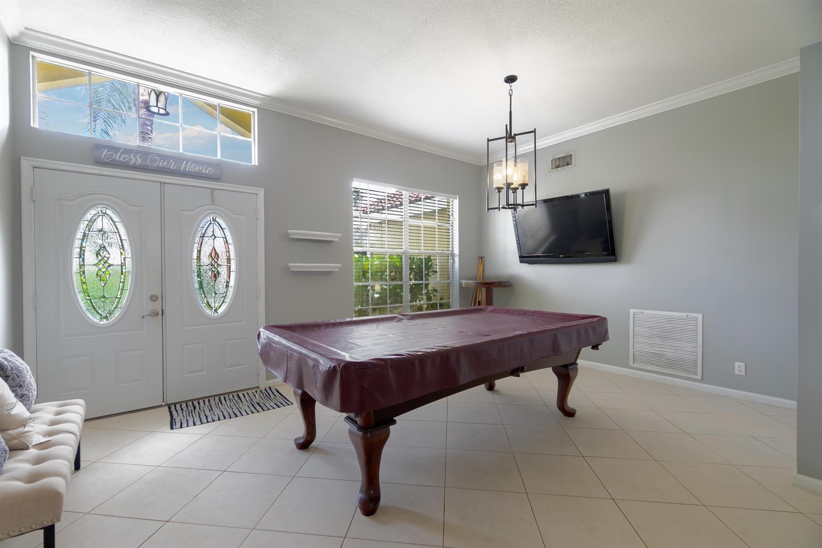 A game room features a pool table, a wall-mounted television, and double entry doors — 149 Cove Road, FL 33413, FL