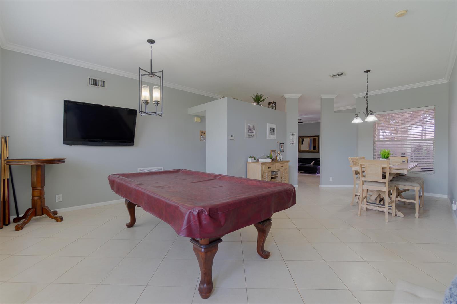 A spacious room features a covered pool table, a dining set, and a wall-mounted television — 149 Cove Road, FL 33413, FL