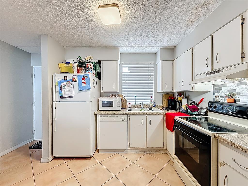 A kitchen featuring white cabinets, white appliances, a tiled floor, and a window above the sink — 6065 NW 186TH STREET UNIT 312, HIALEAH, FL