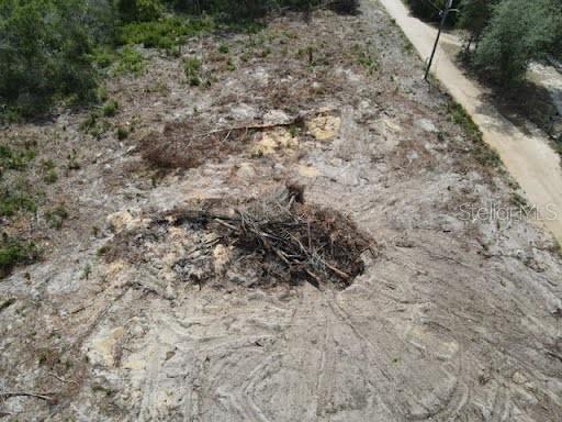 An aerial view of a cleared, sandy plot of land with a pile of debris — Z SE 143RD LN, UMATILLA, FL