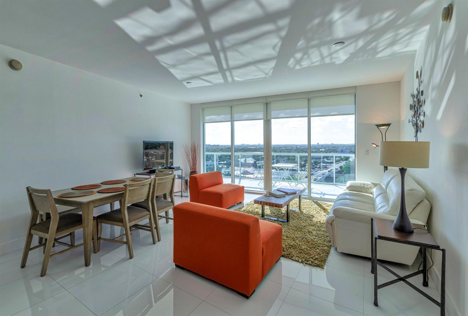 A living and dining area features white tile floors, orange chairs, and a balcony view — 1 N Ocean Boulevard # 913, Pompano Beach FL 33062, POMPANO BEACH, FL