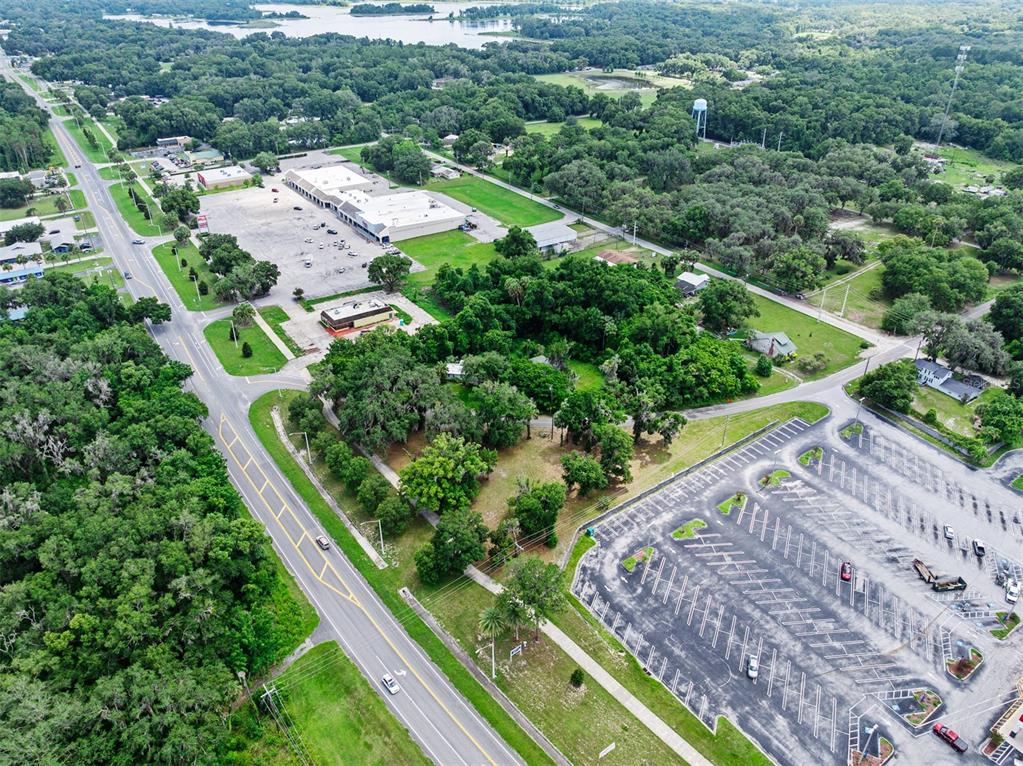 An aerial view shows a commercial plaza, a parking lot, and surrounding wooded areas — 1101 N SUMMIT STREET, CRESCENT CITY, FL