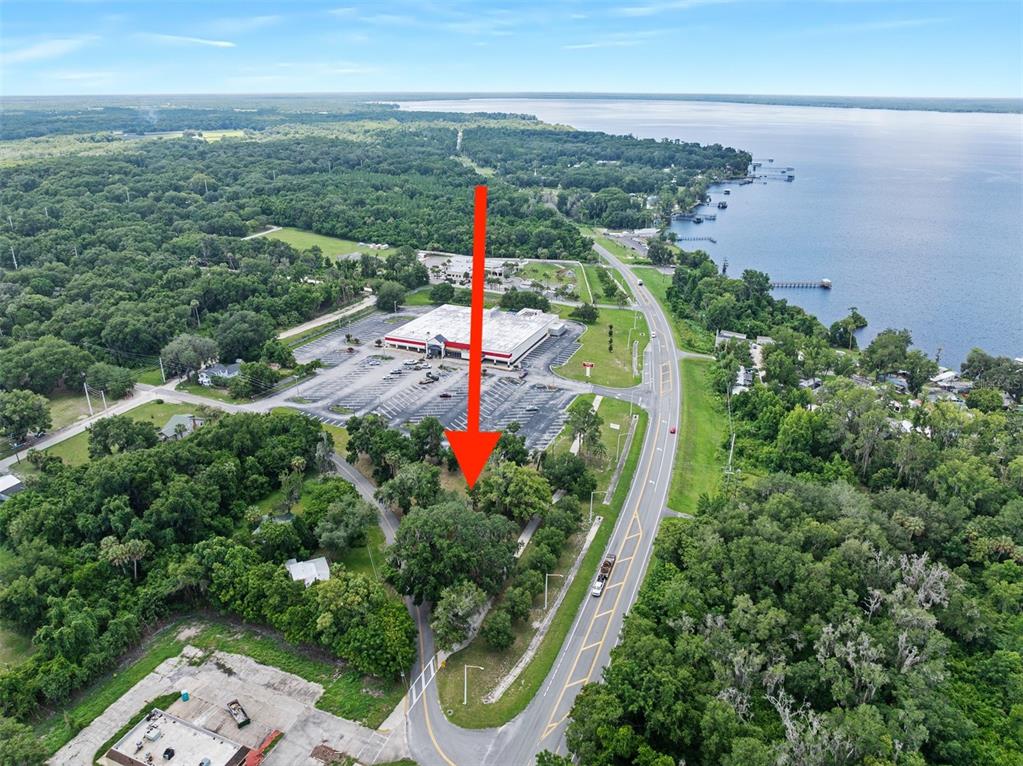 An aerial view shows a wooded lot adjacent to a commercial building and a road — 1101 N SUMMIT STREET, CRESCENT CITY, FL