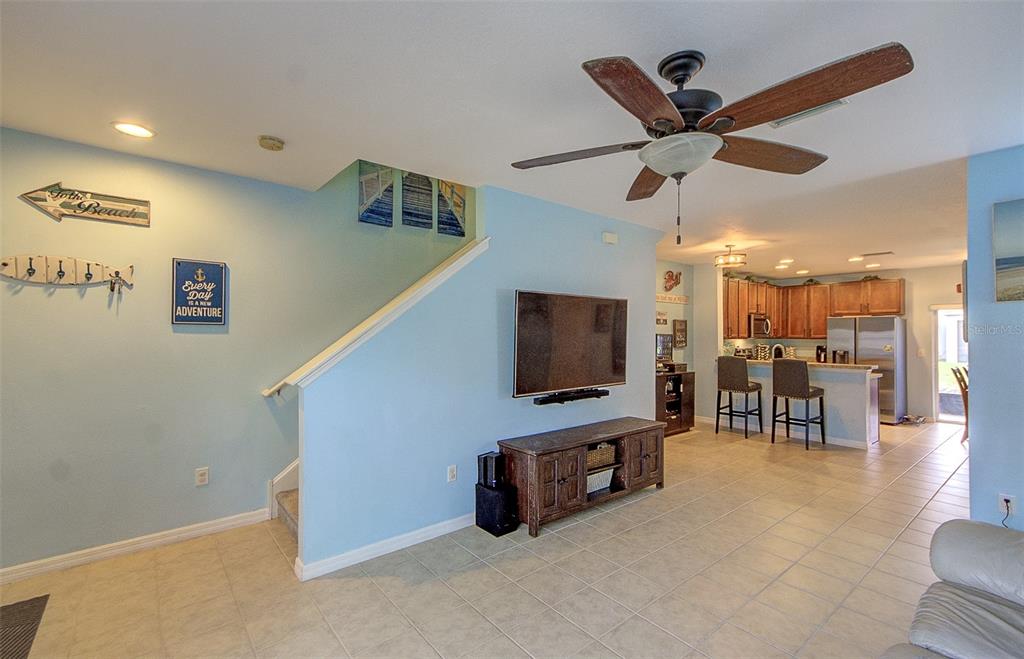 A living room with light blue walls, a staircase, a television, and an open kitchen — 4643 67TH AVENUE N, PINELLAS PARK, FL
