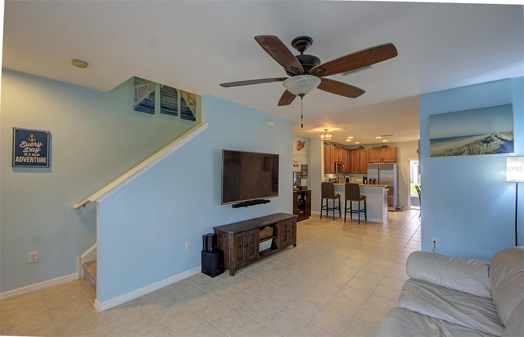 A living room with light blue walls, tile flooring, a ceiling fan, and an open kitchen — 4643 67TH AVENUE N, PINELLAS PARK, FL