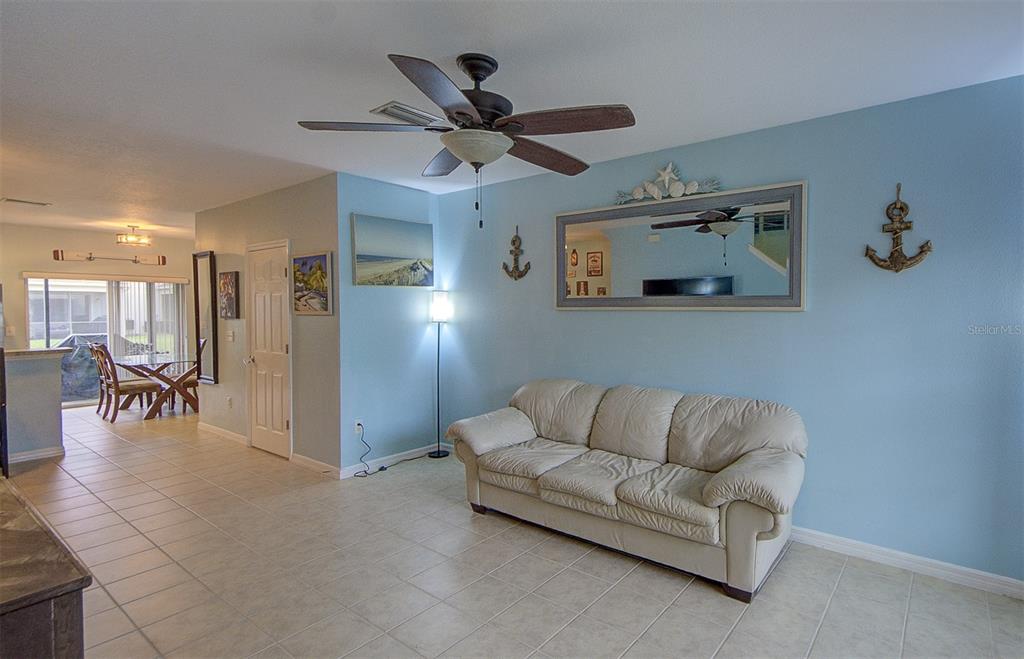A living room with a beige sofa, light blue walls, and a ceiling fan — 4643 67TH AVENUE N, PINELLAS PARK, FL