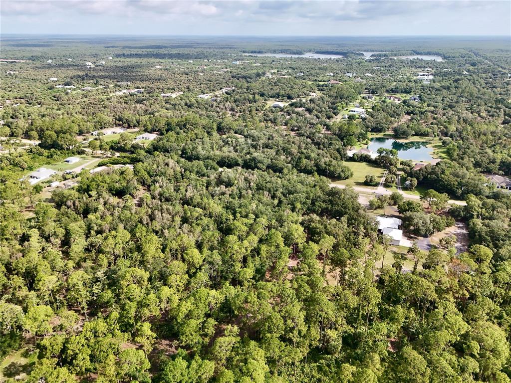 An aerial view shows a wooded landscape with scattered houses and a small pond — 260 35TH AVENUE NW, NAPLES, FL