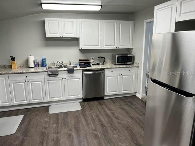 A kitchen features white cabinets, stainless steel appliances, and wood-look flooring — 325 S 2ND STREET UNIT 206, LEESBURG, FL