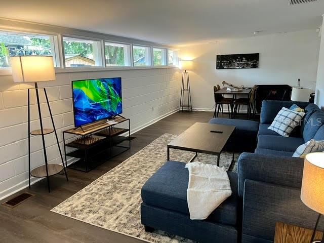 A living room features a blue sectional sofa, a television on a stand, and a dining area — 325 S 2ND STREET UNIT 206, LEESBURG, FL