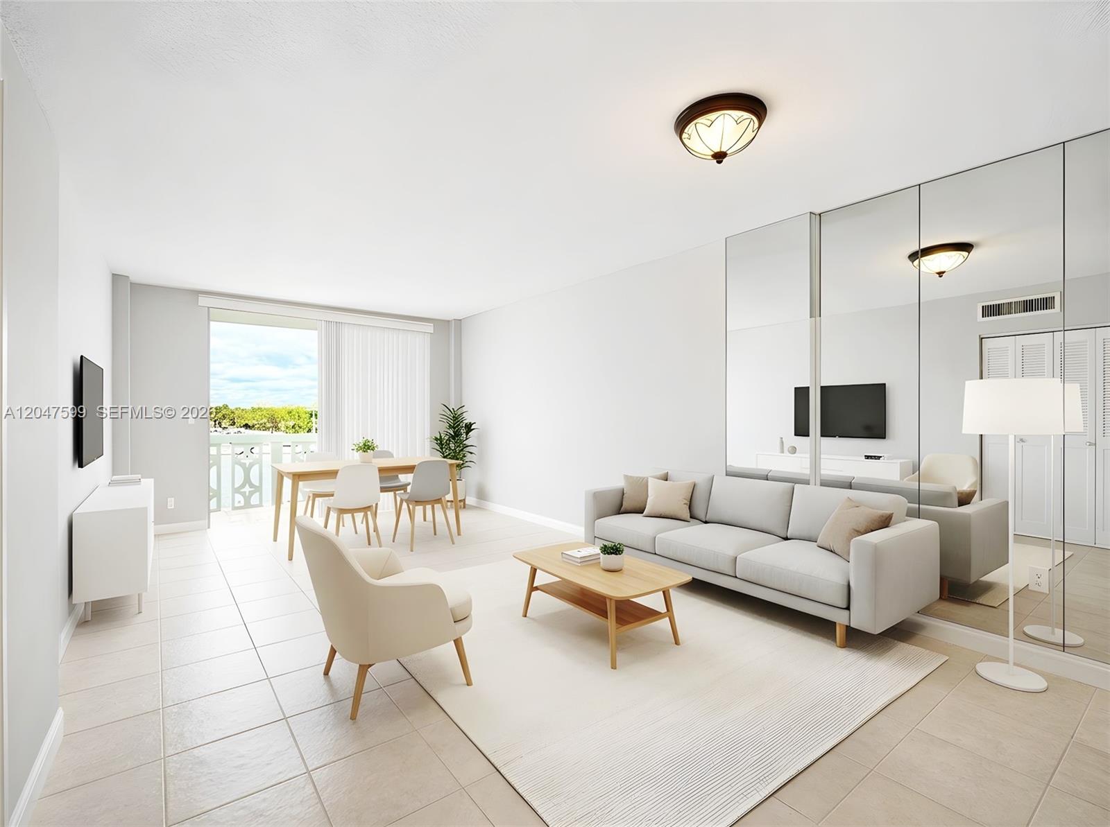 A bright living and dining area features light tile floors, a neutral sofa, and mirrored walls — 13155 Ixora Ct # 310, North Miami FL 33181, NORTH MIAMI, FL