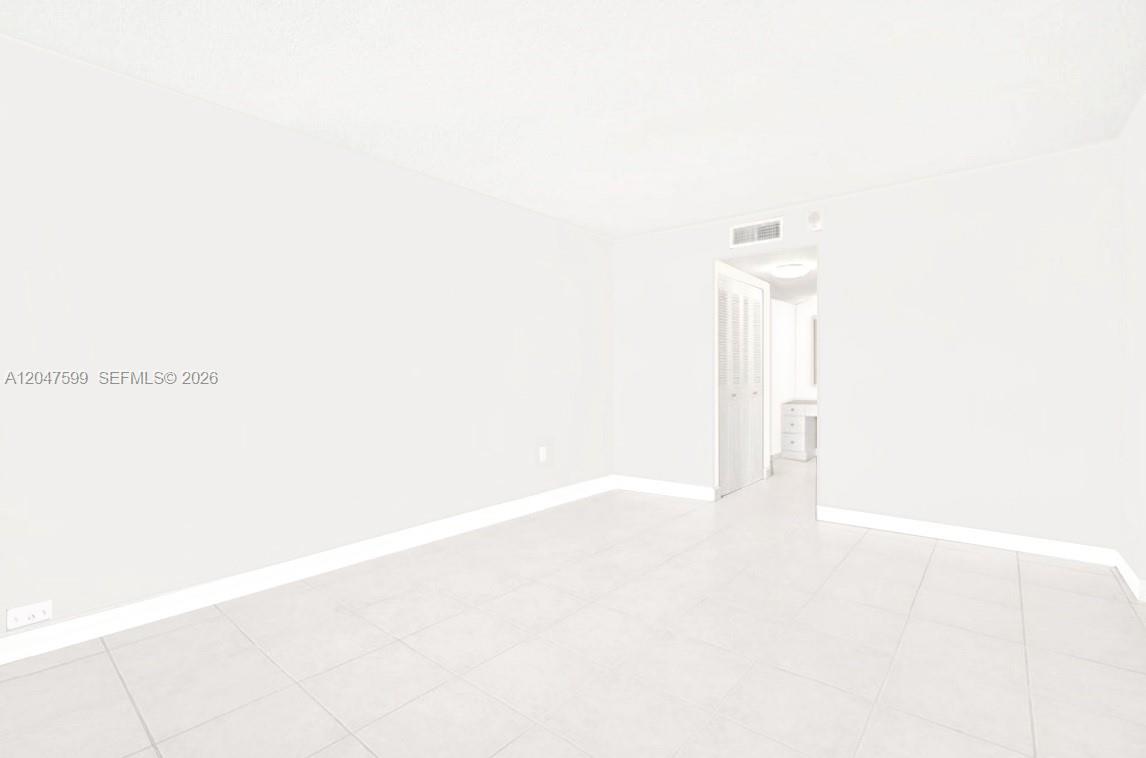 A bright, empty room features white tiled floors, white walls, and a doorway leading inside — 13155 Ixora Ct # 310, North Miami FL 33181, NORTH MIAMI, FL