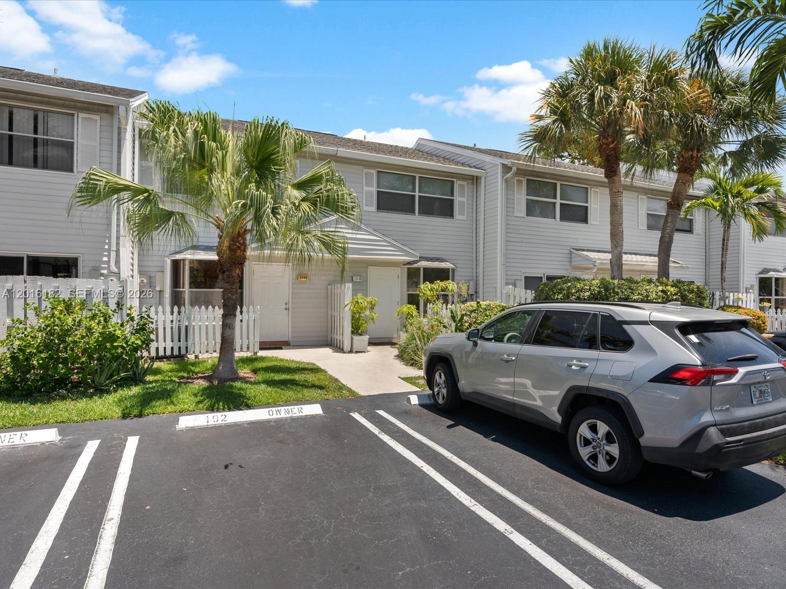 A silver SUV is parked in front of two-story townhouses with white siding and palm trees — 2685 NE 15th St, Pompano Beach FL 33062, POMPANO BEACH, FL