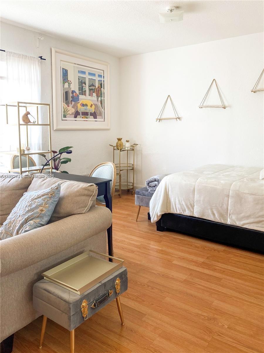 A studio apartment features a bed, a sofa, a desk, and wood-look flooring — 820 Euclid Ave # 203, Miami Beach FL 33139, MIAMI BEACH, FL