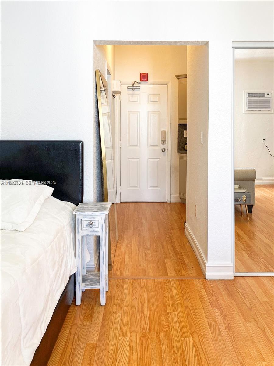 A bedroom features a bed, a small side table, and a doorway leading to an entryway — 820 Euclid Ave # 203, Miami Beach FL 33139, MIAMI BEACH, FL