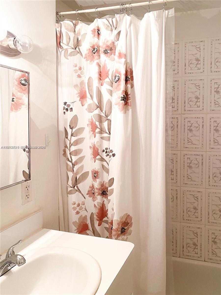 A bathroom features a floral shower curtain, a white vanity, and tiled walls — 820 Euclid Ave # 203, Miami Beach FL 33139, MIAMI BEACH, FL