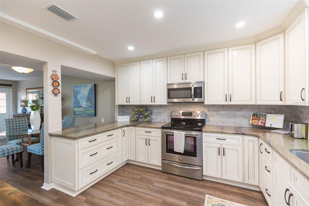 A kitchen with white cabinets, stainless steel appliances, and wood-look flooring — 702 W BAY STREET UNIT A, TAMPA, FL