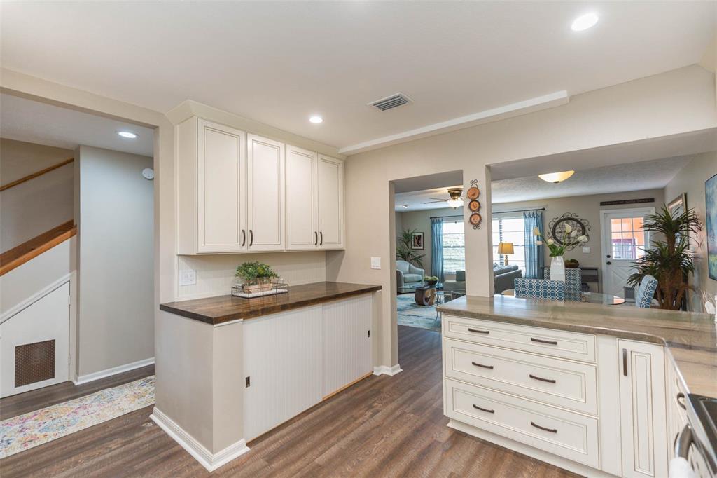 A kitchen features white cabinetry, a dark wood countertop, and a view into the living room — 702 W BAY STREET UNIT A, TAMPA, FL