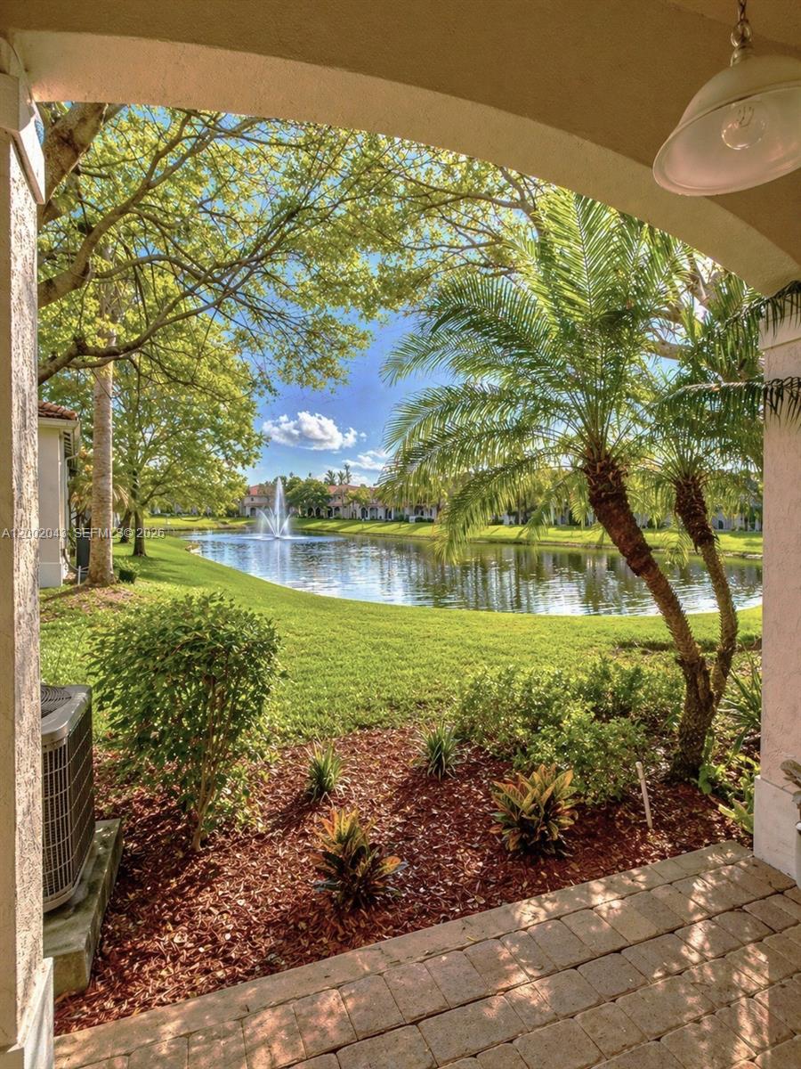 A view from a covered patio overlooking a lake with a fountain and palm trees — 2741 SW 83rd Ave # 104, Miramar FL 33025, MIRAMAR, FL