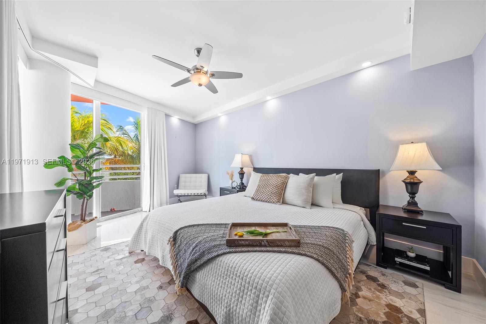 A bedroom features a king bed, a ceiling fan, and a balcony with palm trees — 226 Ocean Dr # 3C, Miami Beach FL 33139, MIAMI BEACH, FL