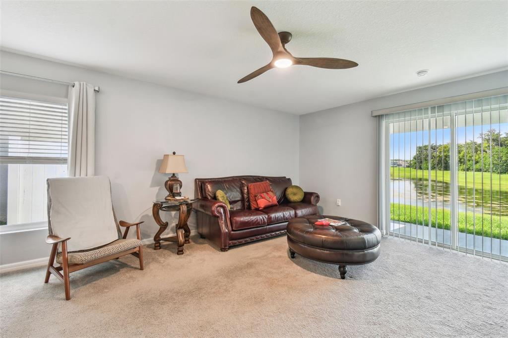 A living room features a leather sofa, a round ottoman, an armchair, and sliding glass doors — 36673 SPANISH ROSE DRIVE, DADE CITY, FL