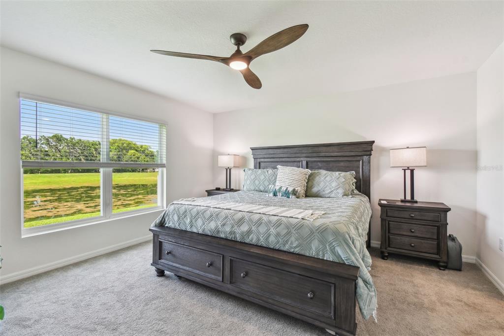 A bedroom features a dark wood bed, two nightstands, a ceiling fan, and a large window — 36673 SPANISH ROSE DRIVE, DADE CITY, FL
