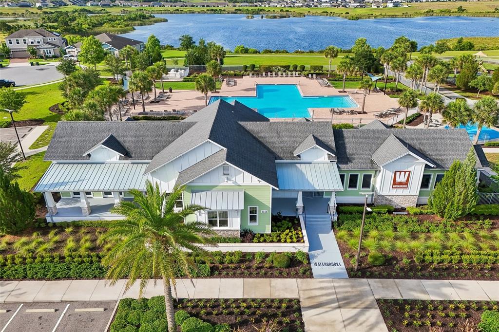 An aerial view shows a community clubhouse with a pool, landscaping, and a nearby lake — 2960 ANGELONIA THORN WAY, CLERMONT, FL