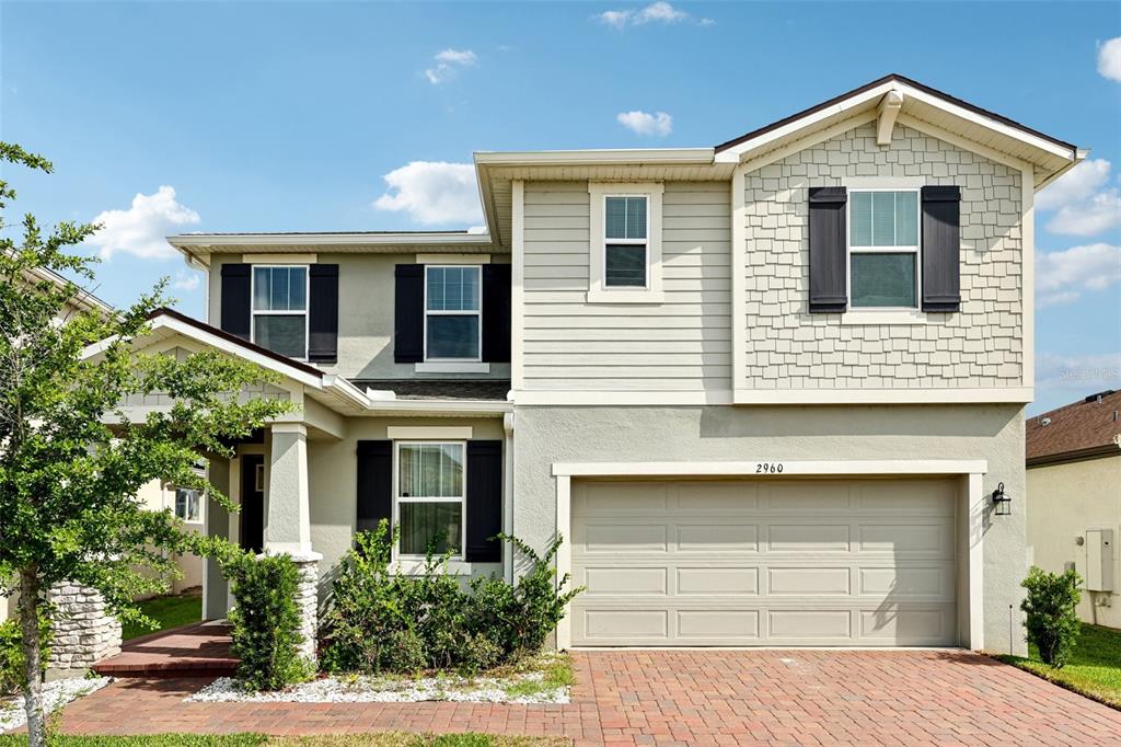 A two-story suburban house features a brick driveway, a garage, and light-colored siding — 2960 ANGELONIA THORN WAY, CLERMONT, FL