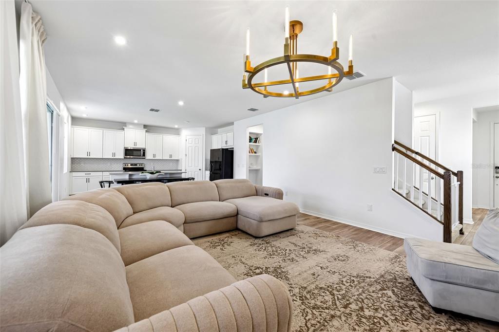 A living room features a large beige sectional sofa, a patterned rug, and a chandelier — 2960 ANGELONIA THORN WAY, CLERMONT, FL