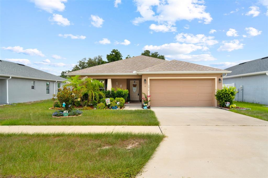 A single-story suburban house with a tan garage, beige siding, and a landscaped front yard — 2014 DANES COURT, LAKELAND, FL