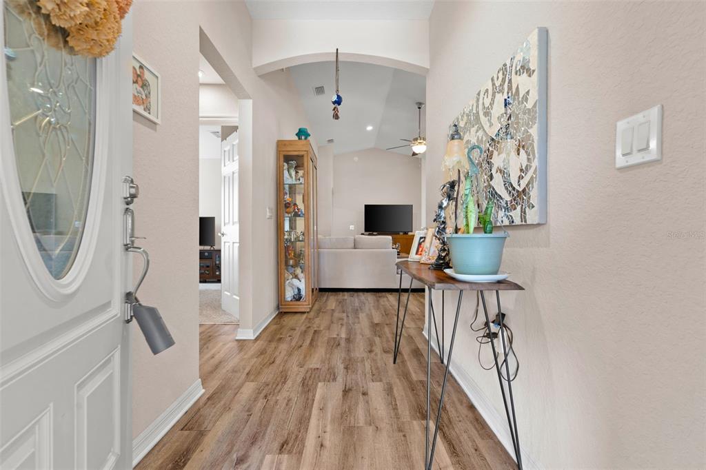 A view from an entryway into a hallway with light wood-look flooring and arched ceilings — 2014 DANES COURT, LAKELAND, FL