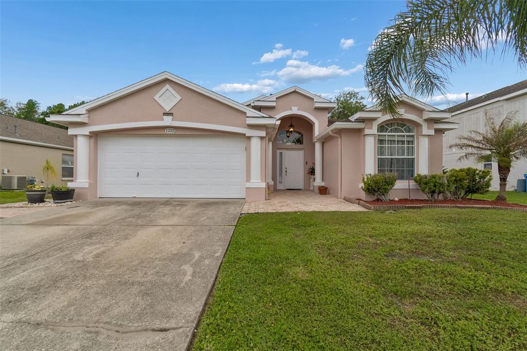 A single-story peach-colored house with a two-car garage and a paved walkway to the entrance — 1223 TIMBER TRACE DRIVE, WESLEY CHAPEL, FL
