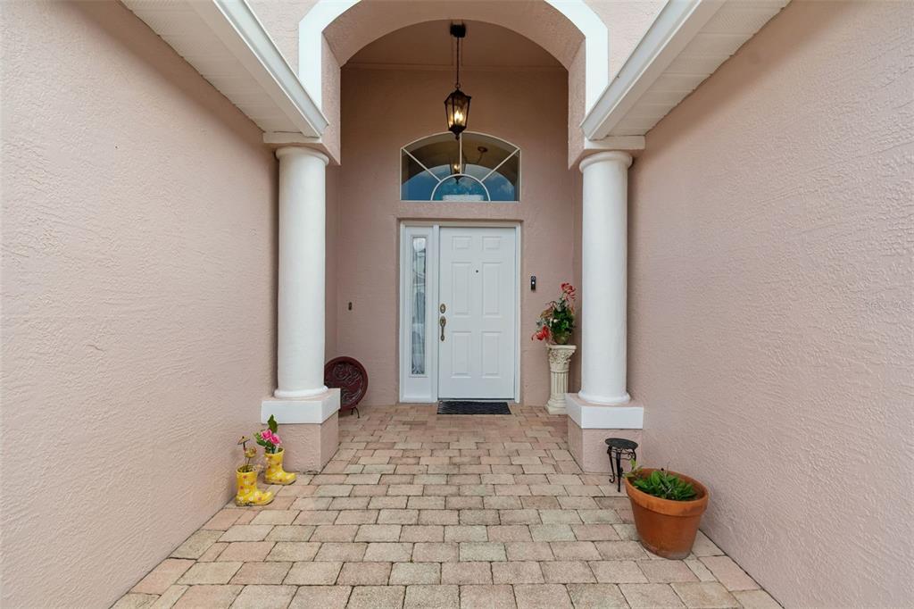 A covered entryway features a white front door, two columns, and a paved stone floor — 1223 TIMBER TRACE DRIVE, WESLEY CHAPEL, FL