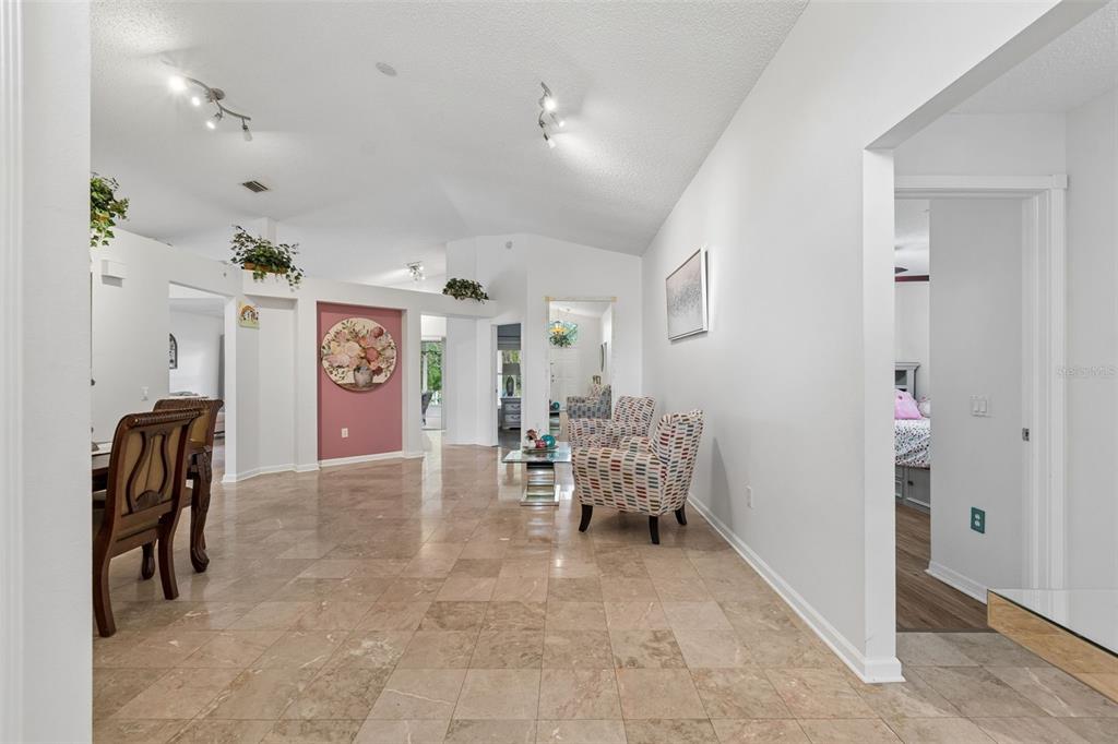 A spacious living area features light tile flooring, white walls, and two patterned armchairs — 1223 TIMBER TRACE DRIVE, WESLEY CHAPEL, FL