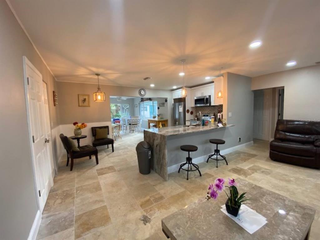 An open-concept kitchen with a stone island, bar stools, and tile flooring — 508 ULELAH AVENUE, PALM HARBOR, FL