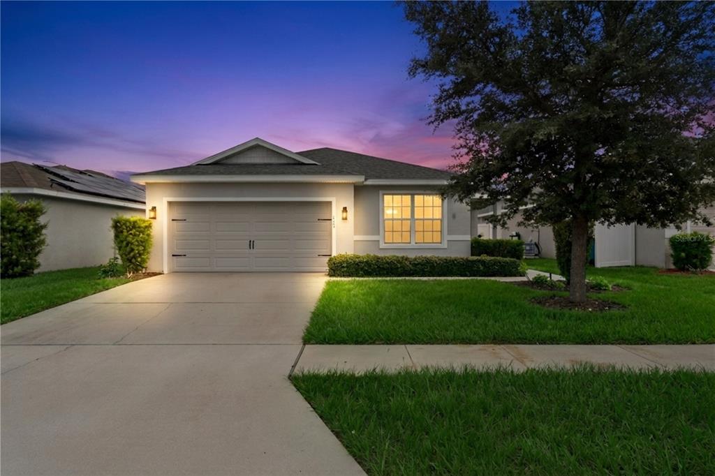 A single-story suburban house with a two-car garage and a front lawn at dusk — 229 SANDESTIN DR, HAINES CITY, FL